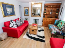 A living room with a red sofa and wooden coffee table at Newgale Cottage in Haverfordwest