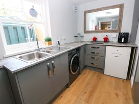 A kitchen with a sink, washing machine, and mirror at Newgale Cottage in Haverfordwest