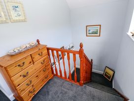 A staircase with a chest of drawers and pictures at Newgale Cottage in Haverfordwest
