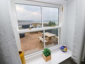 A window view showing a garden seating area and vehicles outside at Newgale Cottage Haverfordwest