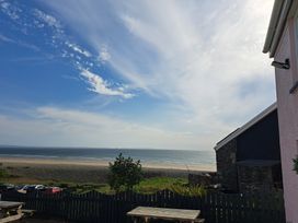 A beach view with tables and ocean at Newgale Cottage in Newgale