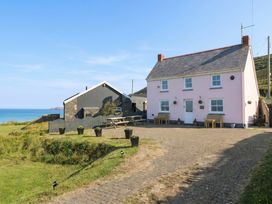 A house and outdoor space with benches and ocean view at Newgale Cottage in Newgale