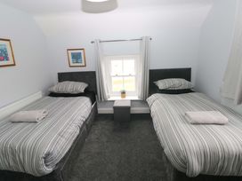 A bedroom with two beds and a window at Newgale Cottage in Newgale