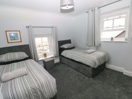 A bedroom with two beds and a window at Newgale Cottage in Newgale