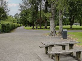 A park with a gravel pathway and a wooden bench at River House 