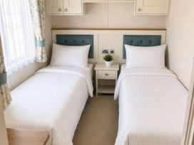 A bedroom with two single beds and a nightstand at Caravan i35 Conwy