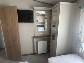 A bedroom with a television and wardrobe at Caravan i35 in Conwy