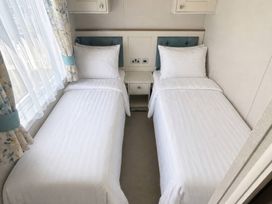 A bedroom with two single beds and a nightstand at Caravan i35 in Conwy