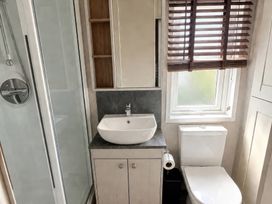 A bathroom with a shower, sink, and toilet at Caravan i35 in Conwy