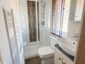 A bathroom with a shower, toilet, and sink at Caravan i35 Conwy