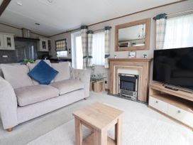 A living room with a sofa and television at Caravan i35 Towyn