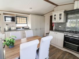 A kitchen with a dining table and chairs at Caravan i35 Towyn