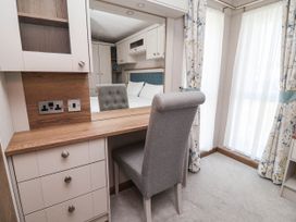 A bedroom with a desk and a chair at Caravan i35 Towyn