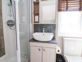 A bathroom with a shower, sink, and toilet at Caravan i35 Towyn