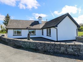 A house with a stone wall and windows at Cahir Cottage in Ballinrobe, County Mayo