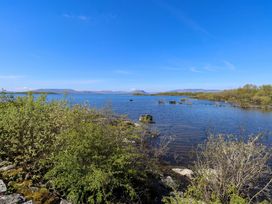 View of a lake with bushes and rocks at Cahir Cottage in Ballinrobe, County Mayo