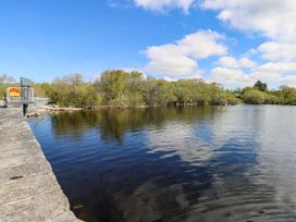 A river with trees and a stone wall near the water at Cahir Cottage Ballinrobe, County Mayo