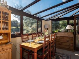 A dining table with chairs and a kitchen cabinet at Trehaverock Cottage St. Endellion near Port Isaac