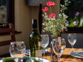 A dining room table set with a wine bottle and glasses at Trehaverock Cottage St. Endellion near Port Isaac
