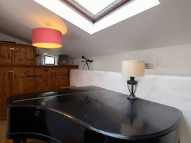 A piano and lamp with cabinets and a telescope in a loft at Trehaverock Cottage St. Endellion near Port Isaac