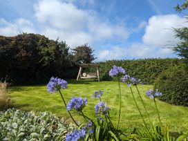 A garden with flowers and a swing at Trehaverock Cottage in St. Endellion near Port Isaac