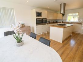 A kitchen with a table and chairs, ovens and a sink at Agan Paradhis in Quintrell Downs