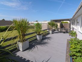 A deck with chairs and table surrounded by planters at Agan Paradhis in Quintrell Downs