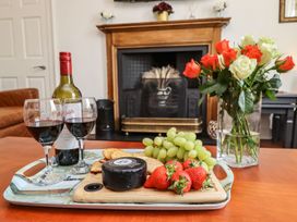 A living room with red wine, cheese, strawberries, and roses at Reighton House in Filey