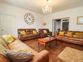A living room with a sofa, coffee table, and clock at Reighton House in Filey