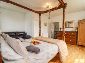 A bedroom with a four-poster bed and a couch at Reighton House in Filey
