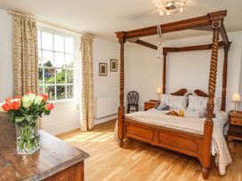 A bedroom with a four-poster bed and a vase of flowers at Reighton House in Filey