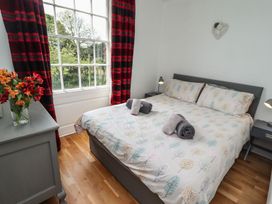 A bedroom with a bed, bedside tables, and a window at Reighton House in Filey