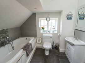 A bathroom with a tub, toilet, and sink at Reighton House in Filey