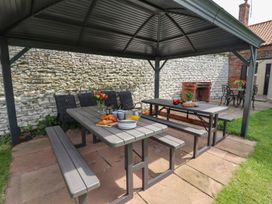 An outdoor dining area with a table and benches at Reighton House in Filey