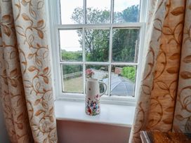 A window with curtains and a flower vase at Reighton House Reighton near Filey