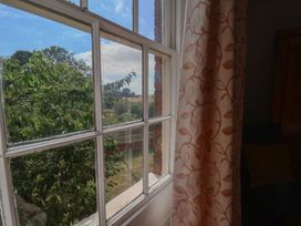 A view from a window with a curtain and trees outside at Reighton House in Reighton near Filey
