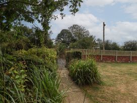 A garden with a pathway leading to a gate at Reighton House in Reighton near Filey