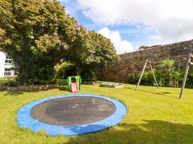 A garden with a trampoline, slide, swing set, and sandbox at Seveock in Threemilestone