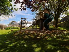 A playhouse with a slide and climbing frame in an outdoor area at Seveock in Threemilestone