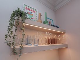 A kitchen shelf with glasses, plant, vases, and books at Apartment Pink