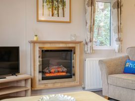 A living room with a fireplace and television at Bingos Cabin in Holt