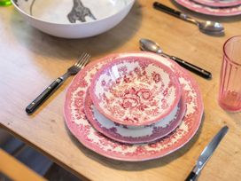 A dining table set with plates, bowls, and utensils at Bingos Cabin in Holt
