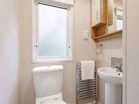 A bathroom with a toilet and sink at Bingos Cabin in Holt