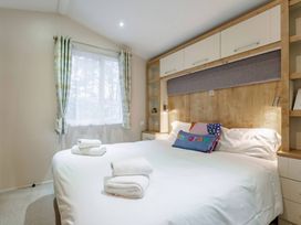 A bedroom with a bed and shelves at Bingos Cabin in Holt