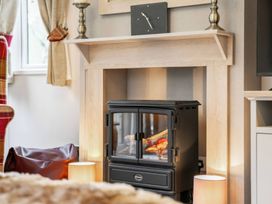 A living room with a stove and lamp at Four Seasons in Holt