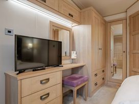 A bedroom featuring a dresser with a TV and a mirror at Four Seasons in Holt