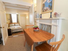 A dining area with a table and chairs and a bedroom in the background at No 3 By The Sea in Weymouth