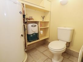 A bathroom with a toilet and a shelf with items at No 3 By The Sea in Weymouth
