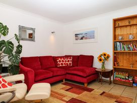 A living room with a red sofa and bookshelf at Gorway Cottage in Teignmouth