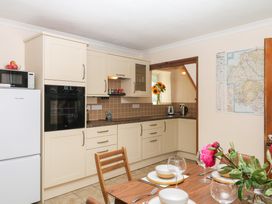 A kitchen with refrigerator, oven, sink, and dining table at Gorway Cottage in Teignmouth